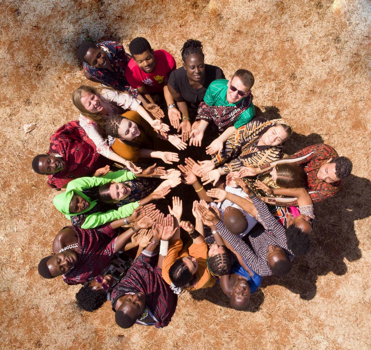 A circle of people seen from above, hands reaching towards the centre