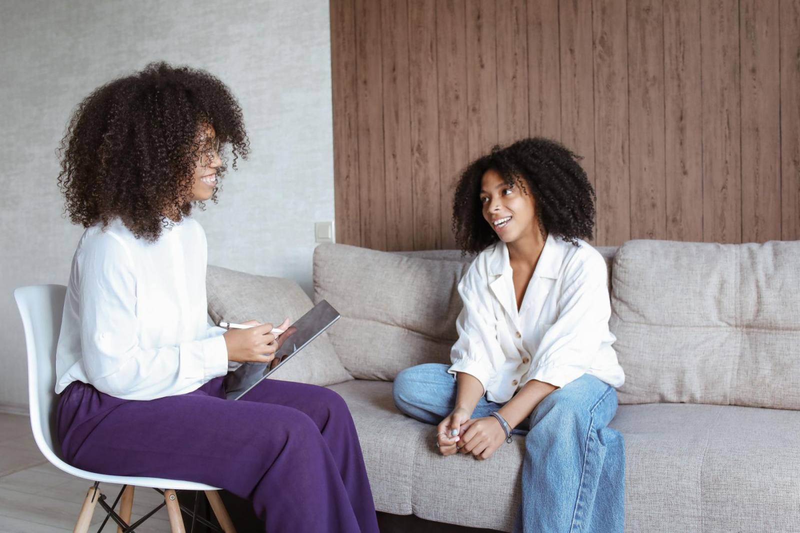 A counsellor listening to a young woman sitting on a sofa
