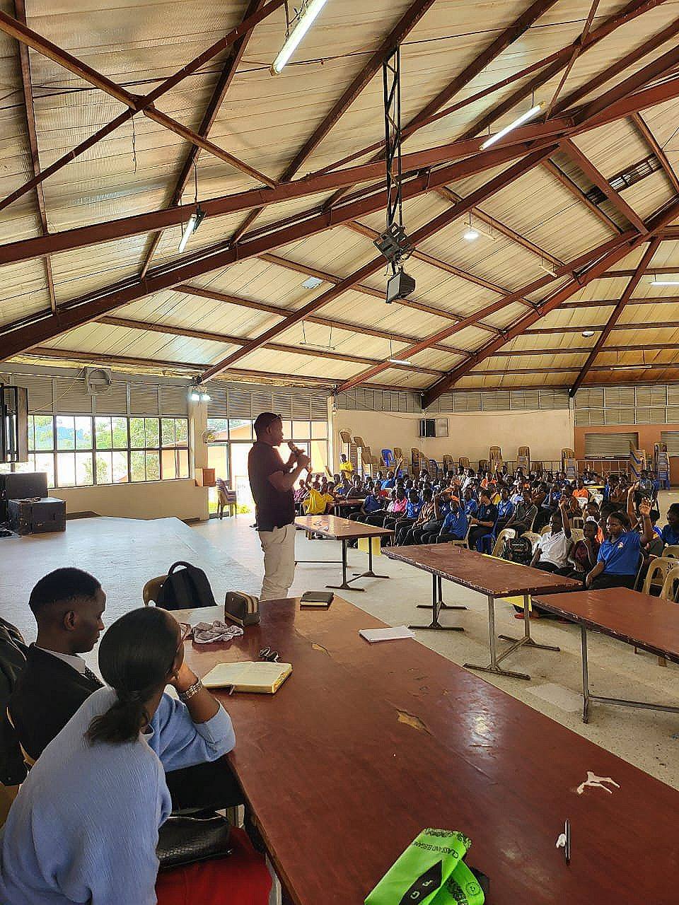 Students in a school hall raising their hands to ask questions during a Voices of Recovery talk