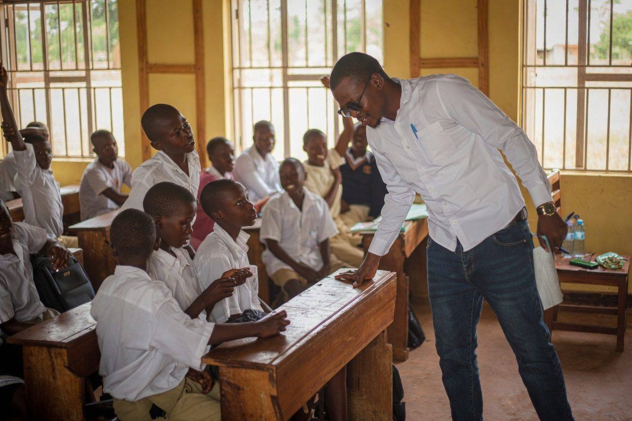 A facilitator talking with secondary school students during a school awareness session
