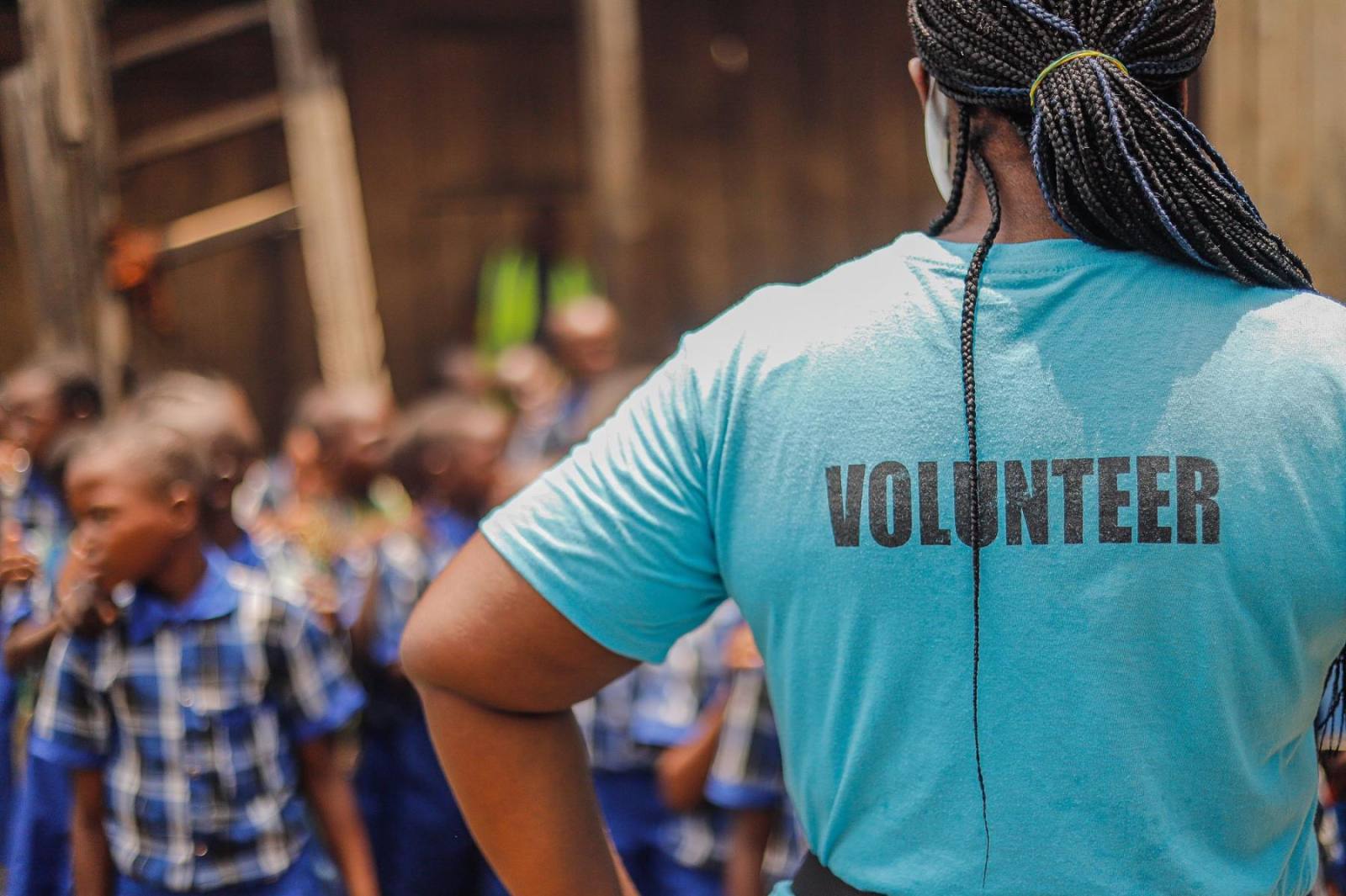 A volunteer in a VOLUNTEER t-shirt standing with a group of schoolchildren