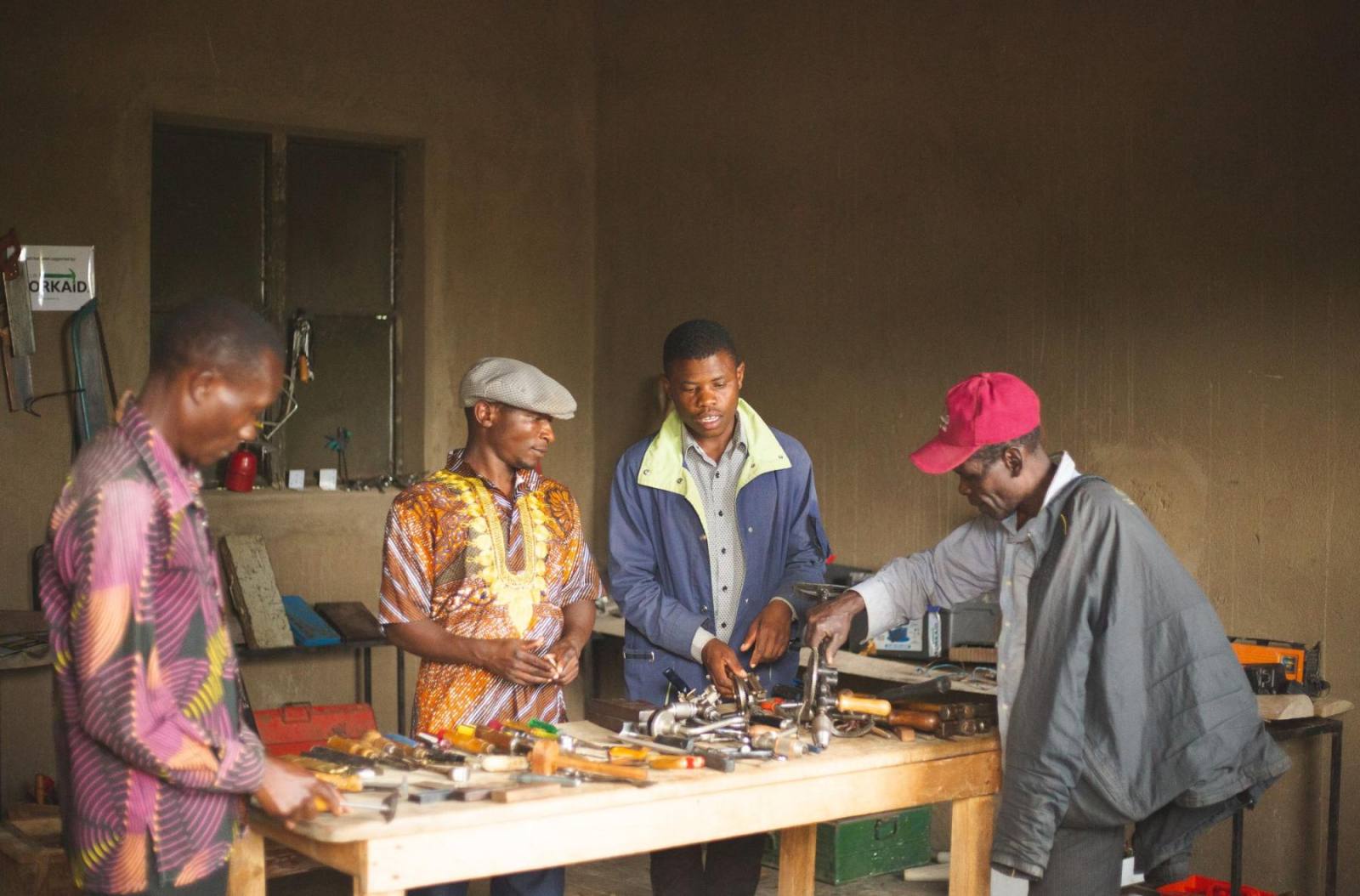 Young men learning practical skills around a workshop table